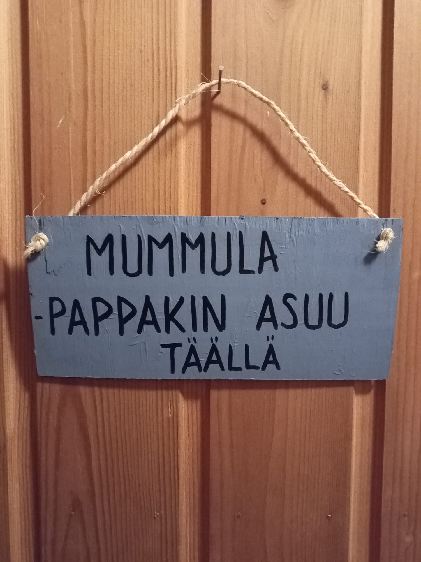 Humoristinen kyltti tekstillä: Mummula-pappakin asuu täällä